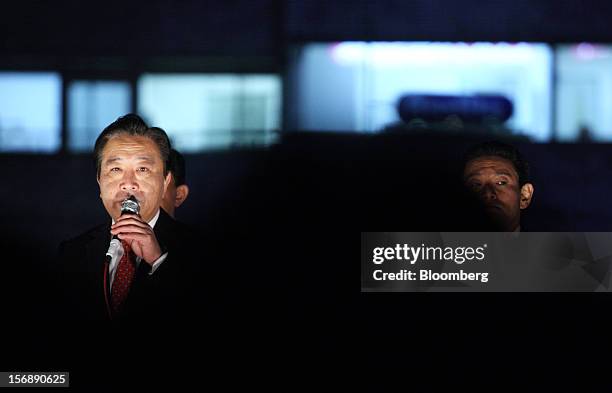 Yoshihiko Noda, Japan's prime minister and president of the Democratic Party of Japan , left, speaks as a security officer looks on during a campaign...