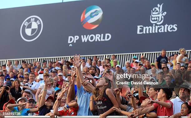 Young fans reach for a ball thrown to the crowd by Luke Donald of England at the 18th green during the third round of the 2012 DP World Tour...