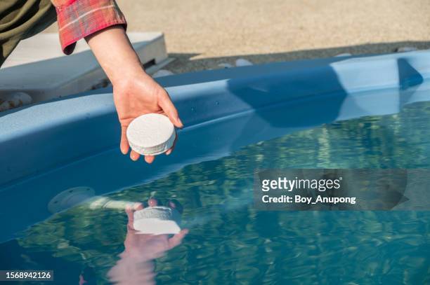 cropped shot of someone hand holding chlorine tablet before throwing in swimming pool. chlorine tablets used for sanitizing pool water and process water systems. - sodium stock pictures, royalty-free photos & images