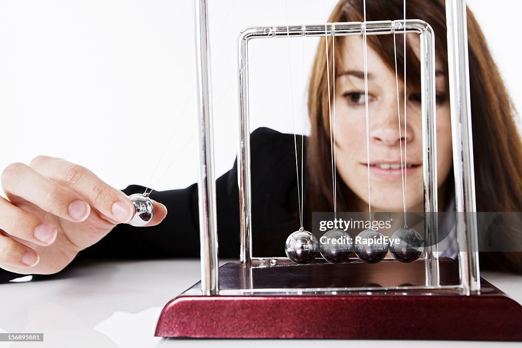 Pretty brunette playing with Newtons Cradle executive toy