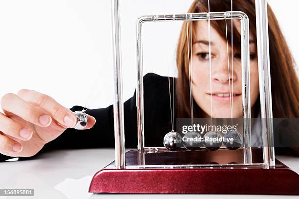 pretty brunette playing with newtons cradle executive toy - newtons cradle stock pictures, royalty-free photos & images