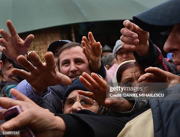 Supporters of Dan Diaconescu Popular Party stretch their hands to get purple scarfs from the party leader Dan Diaconescu during an electoral meeting...