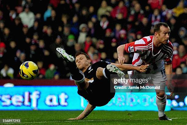 Charlie Adam of Stoke City battles with John Arne Riise of Fulham during the Barclays Premier League match between Stoke City and Fulham at the...