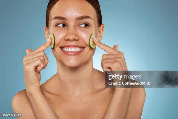 happy young girl with facial mask and slices of cucumber on her face - facial mask stock pictures, royalty-free photos & images