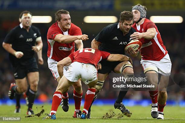 Richie McCaw of New Zealand powers through the challenge of Jonathan Davies , Leigh Halfpenny and Gethin Jenkins of Wales during the International...