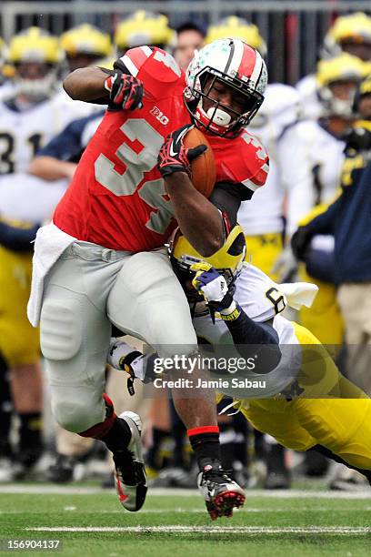 Carlos Hyde of the Ohio State Buckeyes picks up yardage in the second half as Raymon Taylor of the Michigan Wolverines attempts the tackle at Ohio...