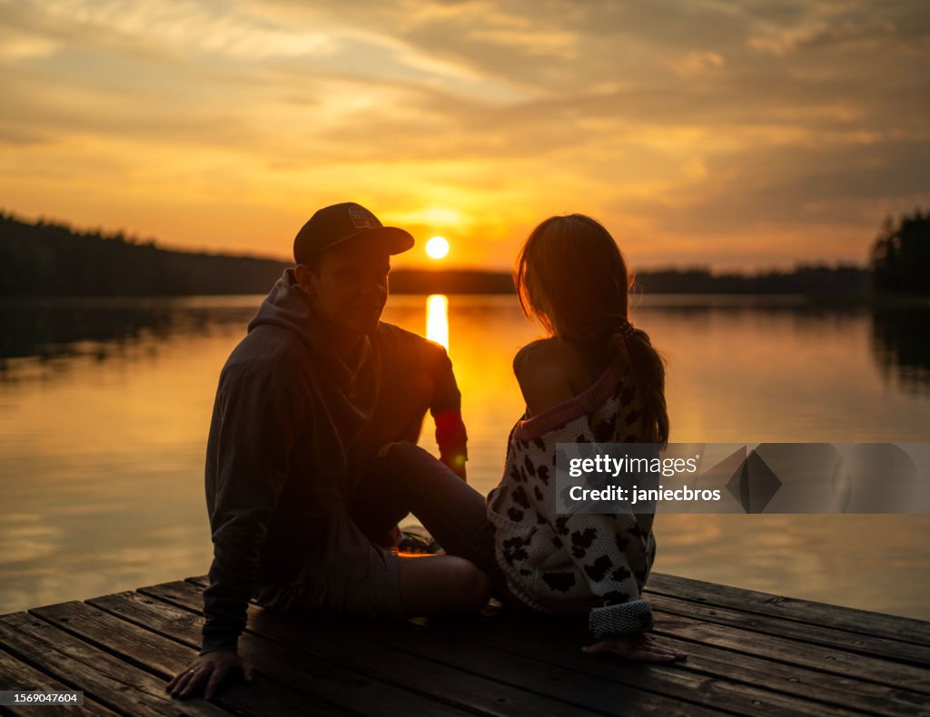 Couple romantique se relaxant sur la jetée. Profiter du paysage du coucher du soleil