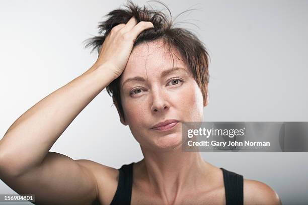 woman with hand in hair - confused woman stockfoto's en -beelden