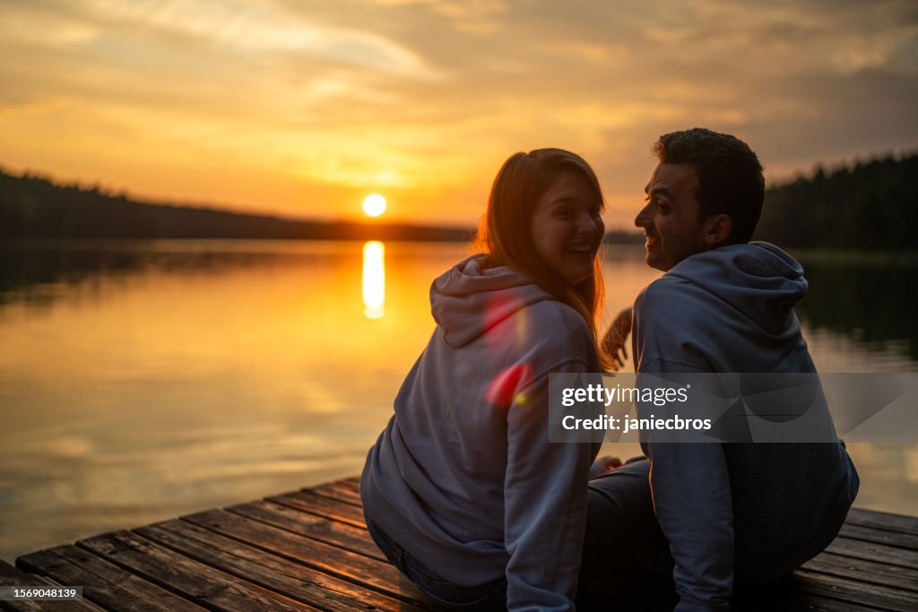 Romantic couple relaxing on the pier. Embracing and enjoying the scenery of lake