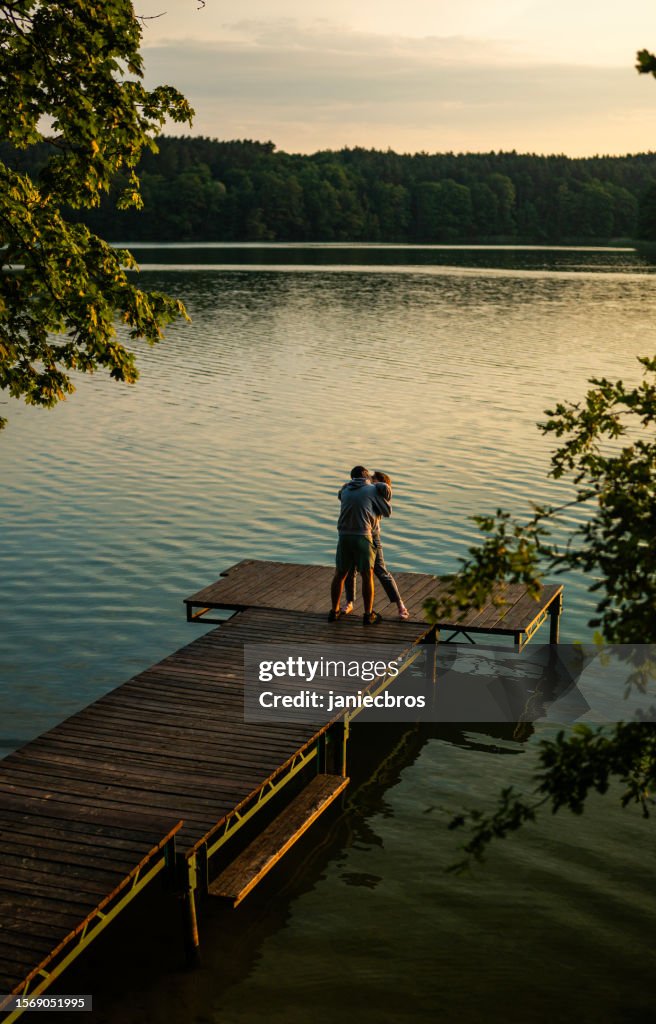 Romantic couple relaxing lying on the pier. Enjoying the scenery of water and forests vertical image