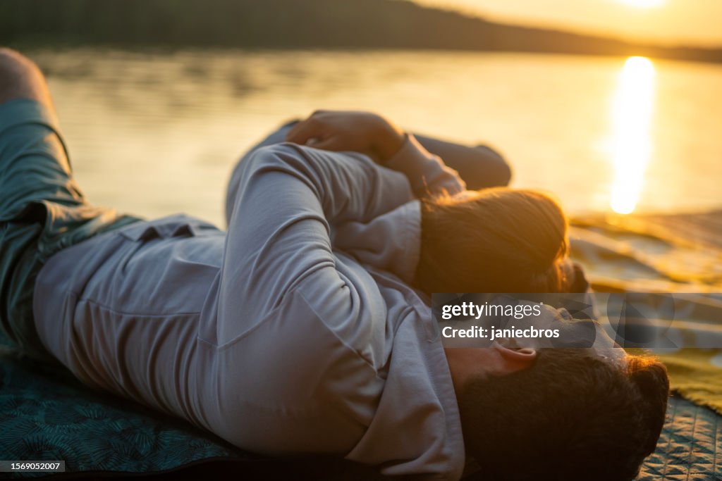 Romantic couple relaxing on the sand by a lake. Enjoying each other and embracing vertical image