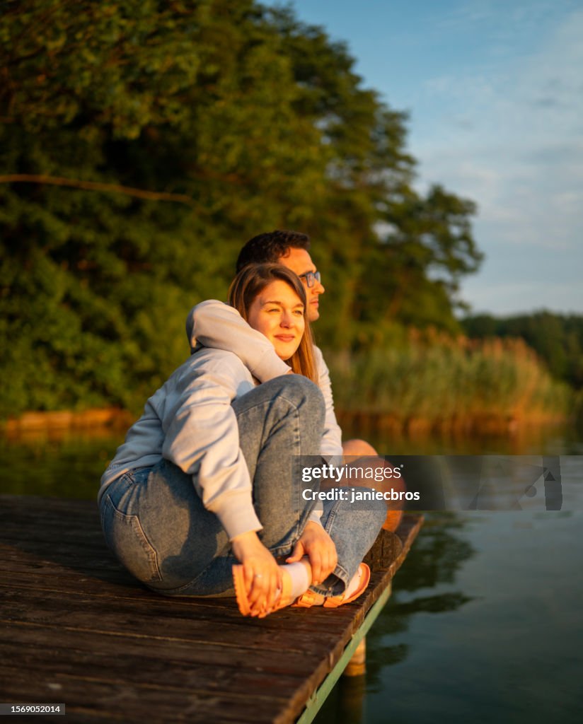 Romantic couple relaxing lying on the pier. Enjoying the scenery
