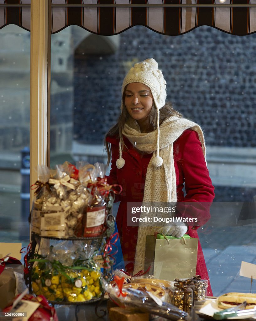 Woman looking through shop window at Christmas.