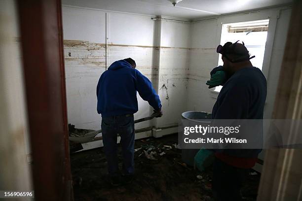 Mark Fischetti , and Mel Firetto shovel sand and trash from a home damaged by Superstorm Sandy, on November 24, 2012 in Seaside Heights, New Jersey....