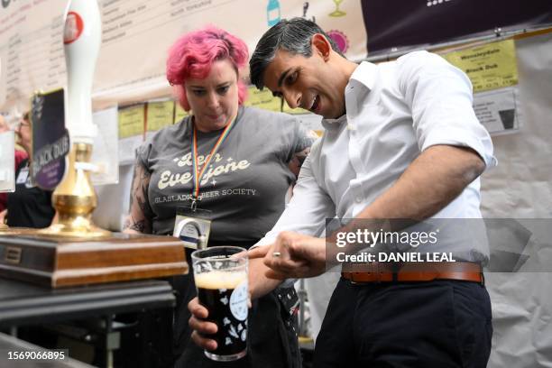 Britain's Prime Minister Rishi Sunak pours a pint of Black Dub stout during a visit to the Great British Beer Festival in west London on August 1,...