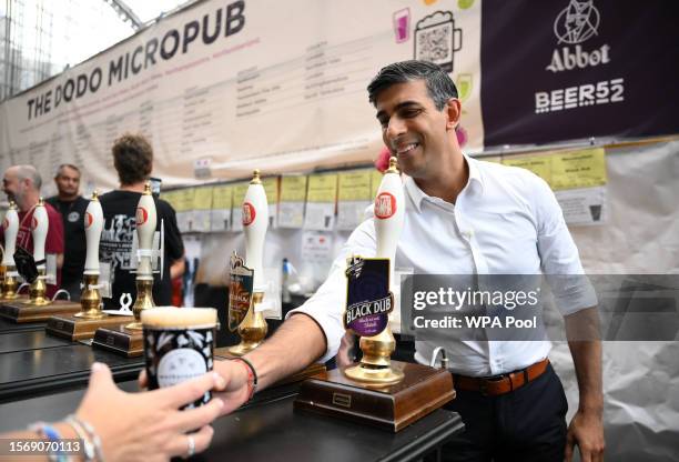 Britain's Prime Minister Rishi Sunak reacts as he serves a pint of Black Dub stout that he poured during a visit to the Great British Beer Festival...