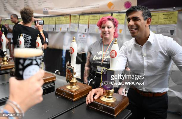 Britain's Prime Minister Rishi Sunak reacts as he serves a pint of Black Dub stout that he poured during a visit to the Great British Beer Festival...