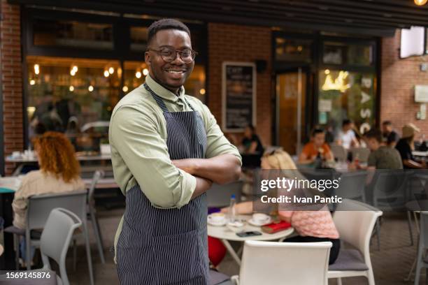 selbstbewusster schwarzer kellner, der in einem café steht. - kantinenfrau stock-fotos und bilder