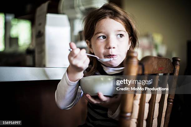 girl (6yrs) eating homemade yogurt from bowl - children eating breakfast stockfoto's en -beelden