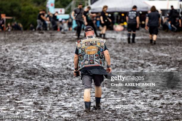 Visitor walks through mud on the festival grounds of the Wacken Open Air music festival in Wacken, northern Germany on August 1 on the eve of the...