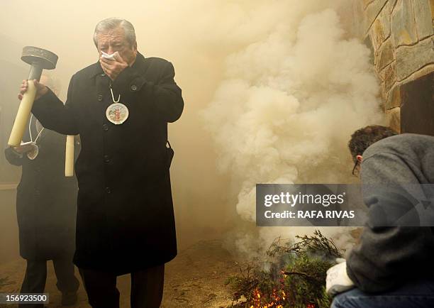 Man covers his mouth as he walks through the smoke of a bonfire with rosemary, on November 25 in the northern Spanish village of Arnedillo prior to...