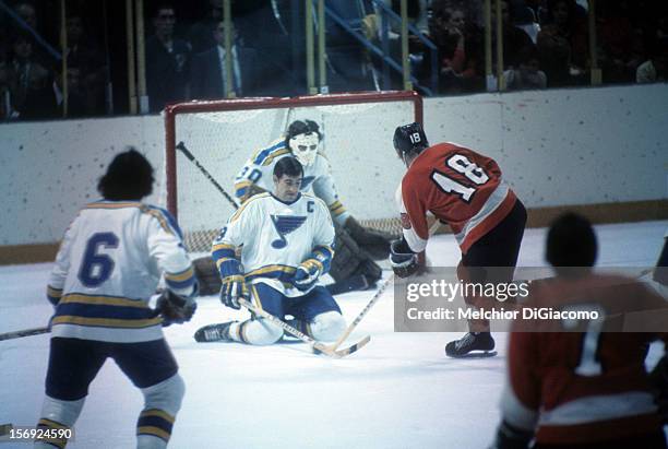 Barclay Plager of the St. Louis Blues blocks the shot of Ross Lonsberry of the Philadelphia Flyers circa 1972 at the St. Louis Arena in St. Louis,...