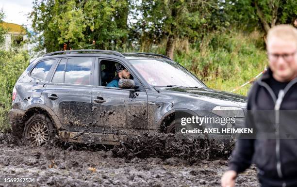 Festival-goer tries to park his car on the muddy festival grounds on the eve of the opening of the Wacken Open Air music festival in Wacken, northern...