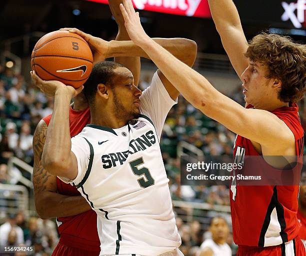 Adreian Payne of the Michigan State Spartans tries to get a pass out to a teammate through the defense of Steven Wronkoski of the Louisiana-Lafayette...