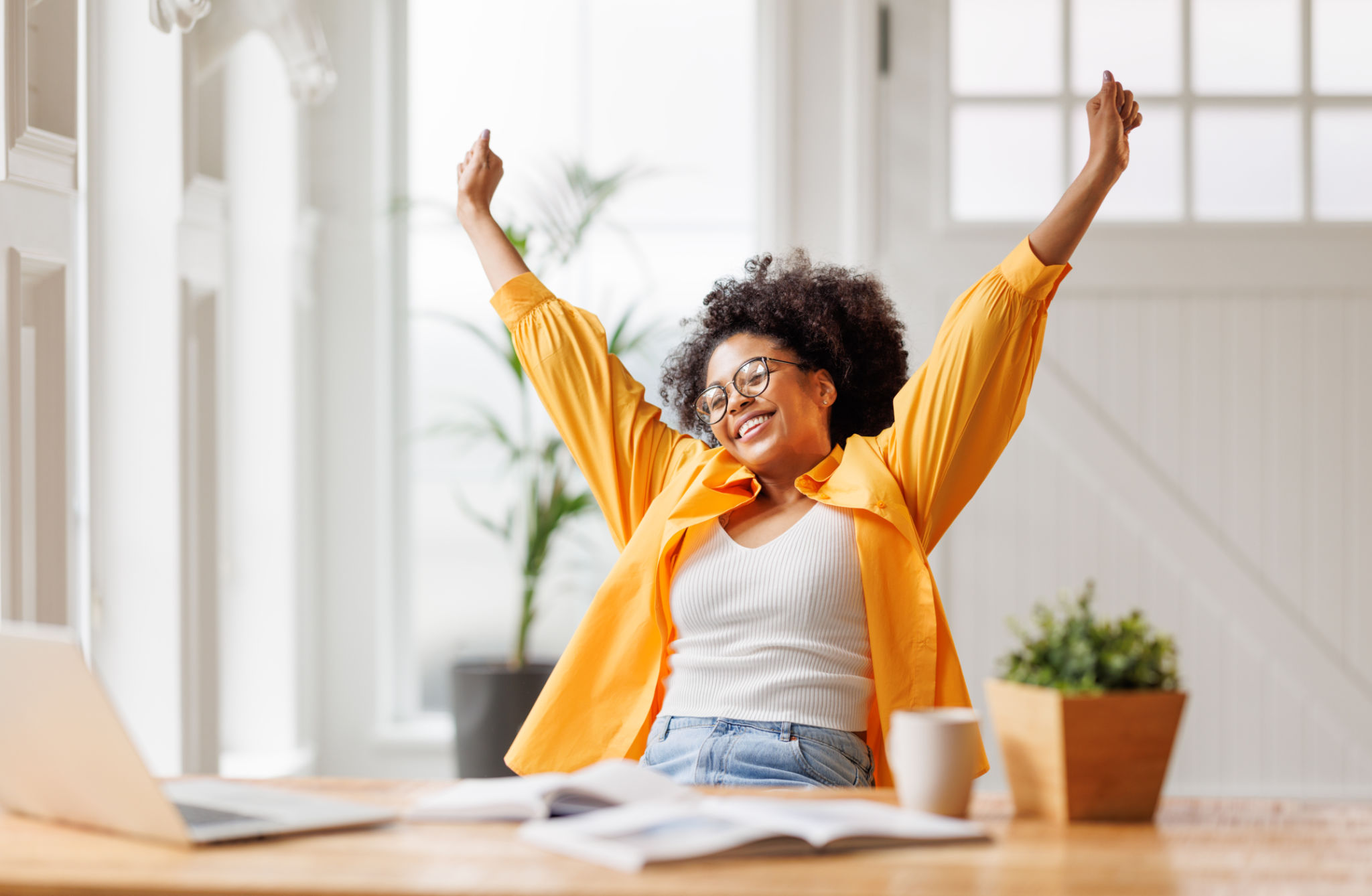 Joyful business woman freelancer entrepreneur smiling and rejoices in victory while sitting at desk and working at laptop after finishing project in home office Joyful business woman freelancer entrepreneur smiling and rejoices in victory while sitting at desk and working at laptop after finishing project in home office
