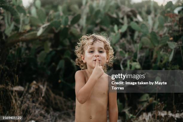 boy in front of cactus putting a finger in his mouth - kid putting finger in mouth stock-fotos und bilder