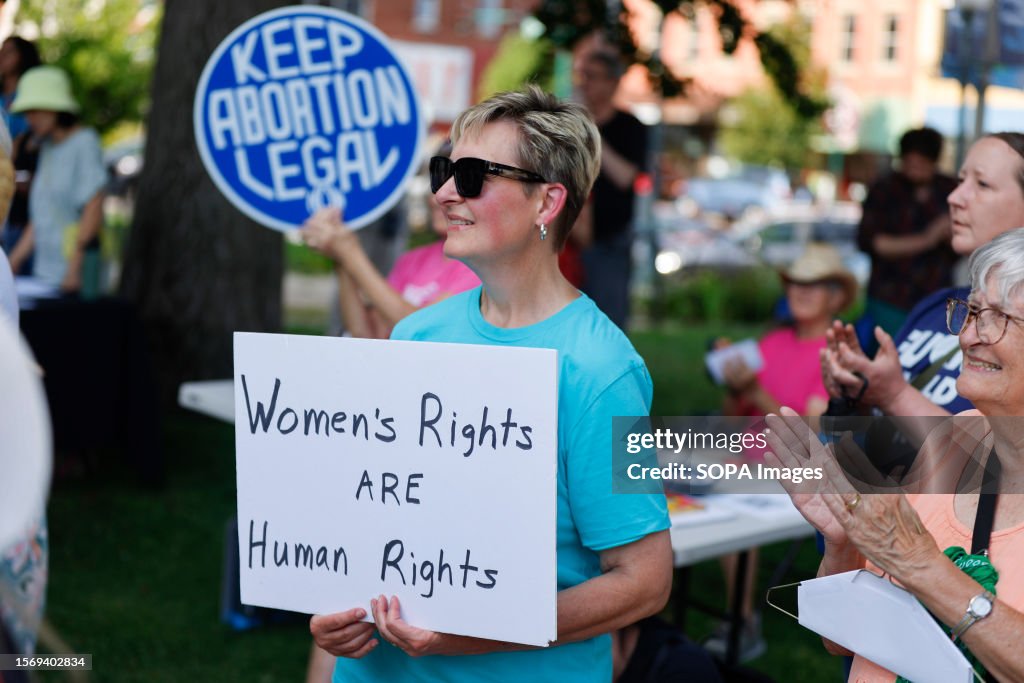 A woman holds a placard saying , "Women's Rights ARE...