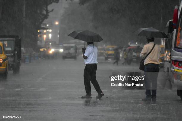 People are seen during heavy rainfall in Kolkata , India , on 1 August 2023 .