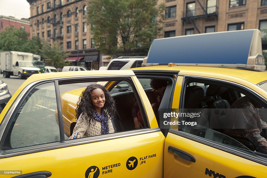 Tween girl getting into cab and smiling