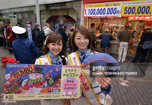 Campaign staff Mayuka Nakatani and Kumiko Wakai display sample lottery tickets as people queue to purchase tickets for the 600 million yen year-end...