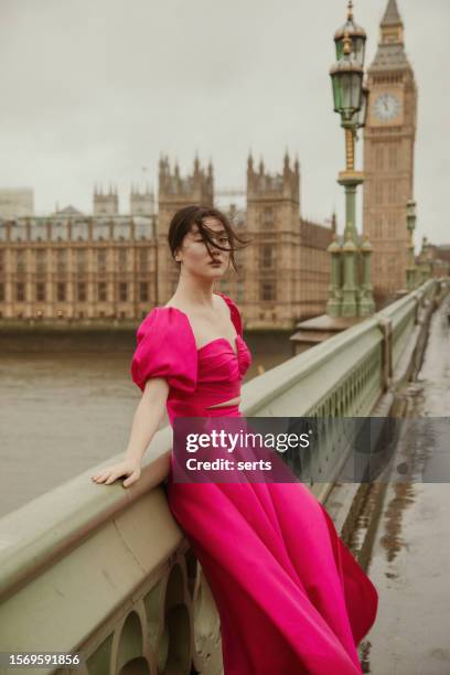 graceful fashion model embracing the elements at westminster bridge with big ben, elizabeth tower, and parliament building on a windy, rainy day - collection launch street style stock pictures, royalty-free photos & images