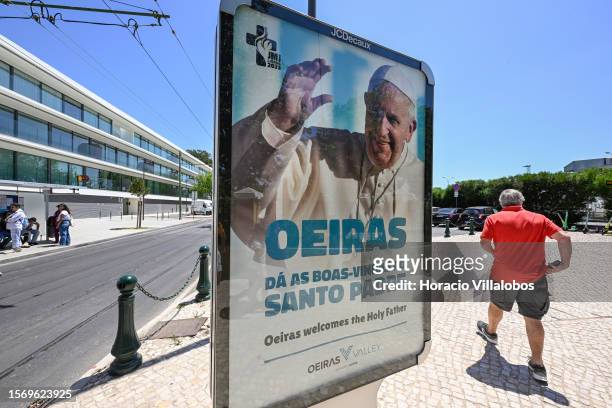 Man walks past a poster showing a smiling Pope Francis at a bus stop in Rua Sacadura Cabral welcoming him for World Youth Day ceremonies that will...