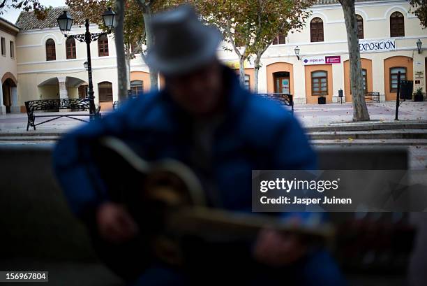 Man plays his guitar trying to make money on an empty Plaza Mayor on November 23, 2012 in Villacanas, Spain. During the boom years, where in its peak...