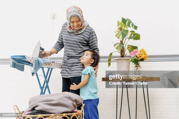 asian women ironing clothes with her daughter - hijab feet stock pictures, royalty-free photos & images