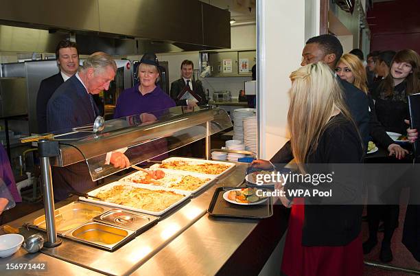 Prince Charles, Prince of Wales serves rhubarb crumble to Rosir Wastell during a visit to Carshalton Boys Sports College with Jamie Oliver to see how...