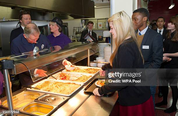 Prince Charles, Prince of Wales serves rhubarb crumble to Rosir Wastell during a visit to Carshalton Boys Sports College with Jamie Oliver to see how...