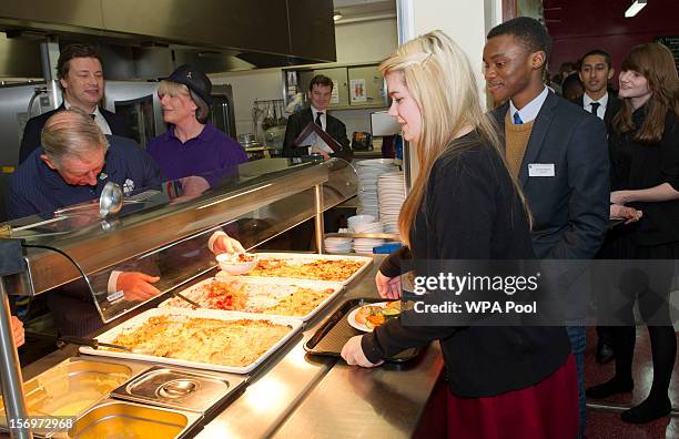 Prince Charles, Prince of Wales serves rhubarb crumble to Rosir Wastell during a visit to Carshalton Boys Sports College with Jamie Oliver to see how...