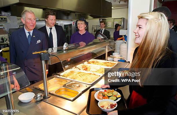 Prince Charles, Prince of Wales shares a joke with Rosir Wastell after serving rhubarb crumble during a visit to Carshalton Boys Sports College with...