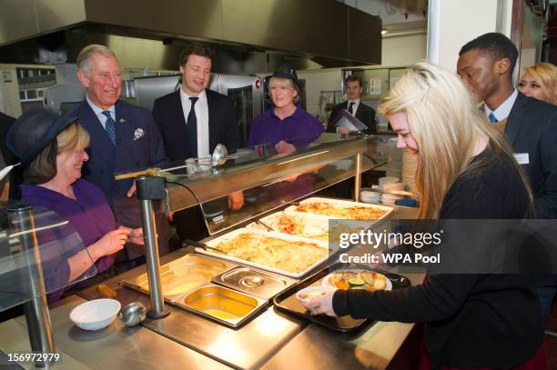 Prince Charles, Prince of Wales shares a joke with Rosir Wastell after serving rhubarb crumble during a visit to Carshalton Boys Sports College with...