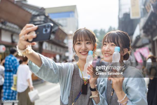 jóvenes amigas con el atuendo tradicional japonés matsuri tomándose una foto selfie con refrescos en la calle - autorretratarse fotografías e imágenes de stock