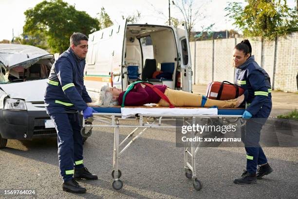 ambulance team moving accident victim on portable gurney - stretcher stock pictures, royalty-free photos & images