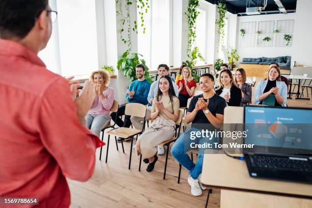audience applauding after watching presentation together - oficio de educación fotografías e imágenes de stock