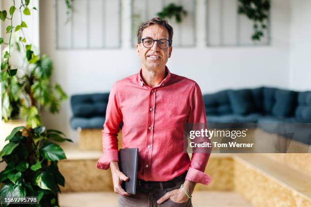 portrait of smiling seminar host holding laptop - red shirt stock pictures, royalty-free photos & images