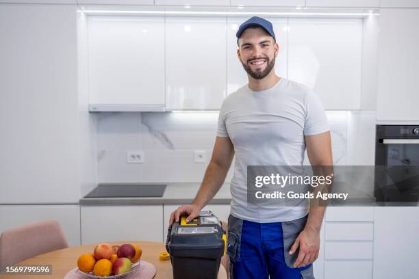 handyman standing by toolbox and smiling - handyman stockfoto's en -beelden