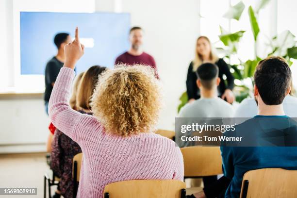 woman raising hand to aske question during presentation - chiedere foto e immagini stock