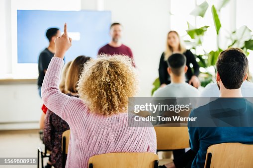 Woman Raising Hand To Aske Question During Presentation Woman Raising Hand To Aske Question During Presentation